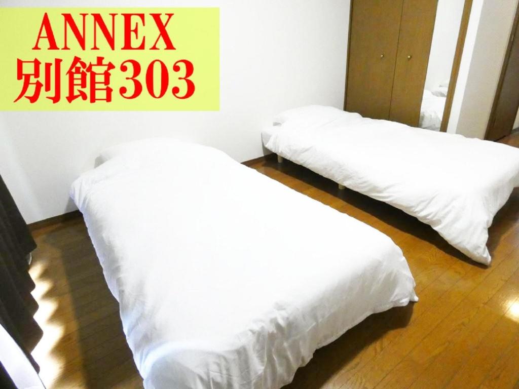 筑紫野市AO Dazaifu / Vacation STAY 61718的墙上有标牌的房间,配有两张白色的床