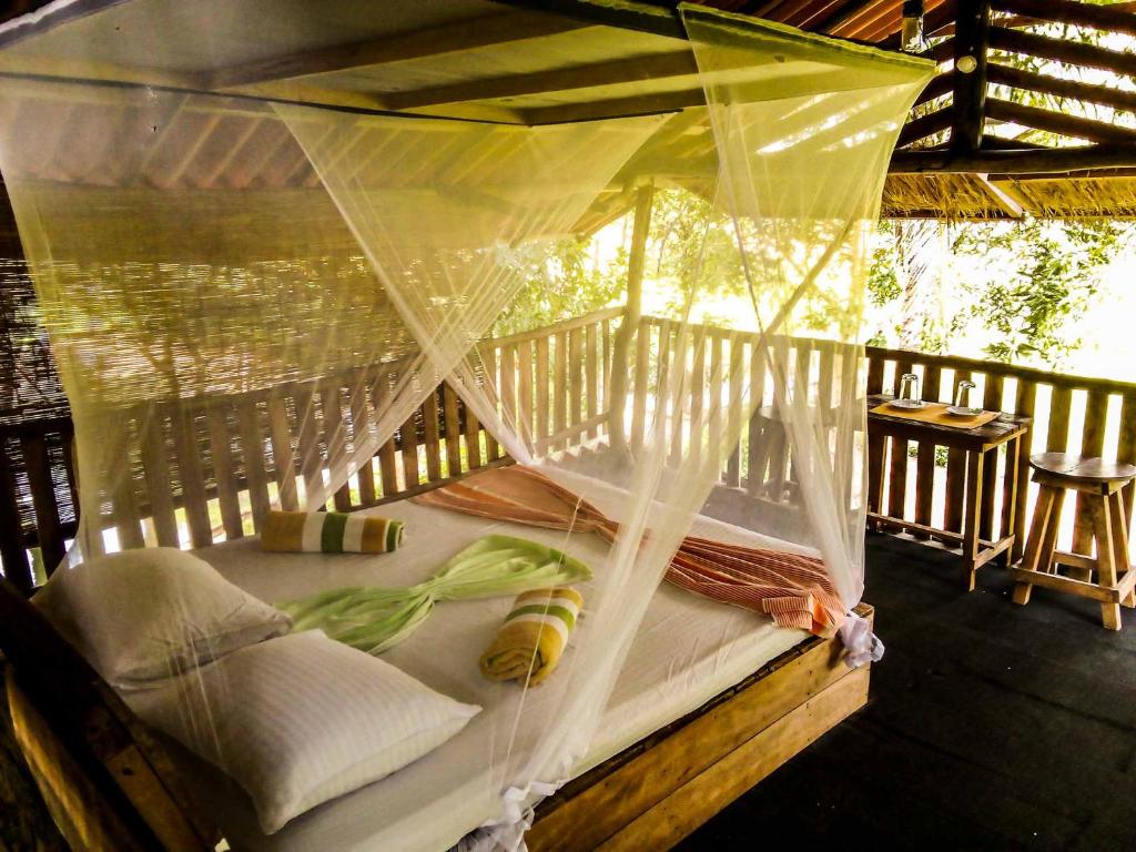 哈伯勒内Habarana Eco Lodge & Safari的门廊上的一张床铺,带蚊帐