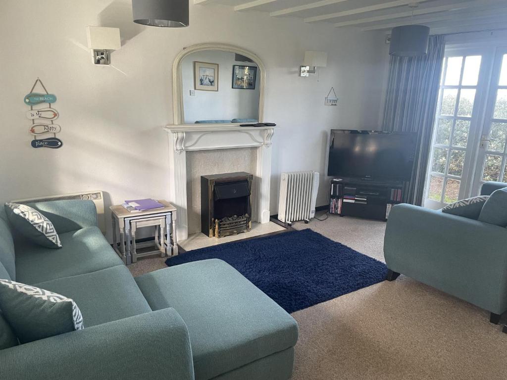 海尔Tudor Cottage Hayle - a Family & Pooch Favourite的客厅配有2张蓝色沙发和1台电视