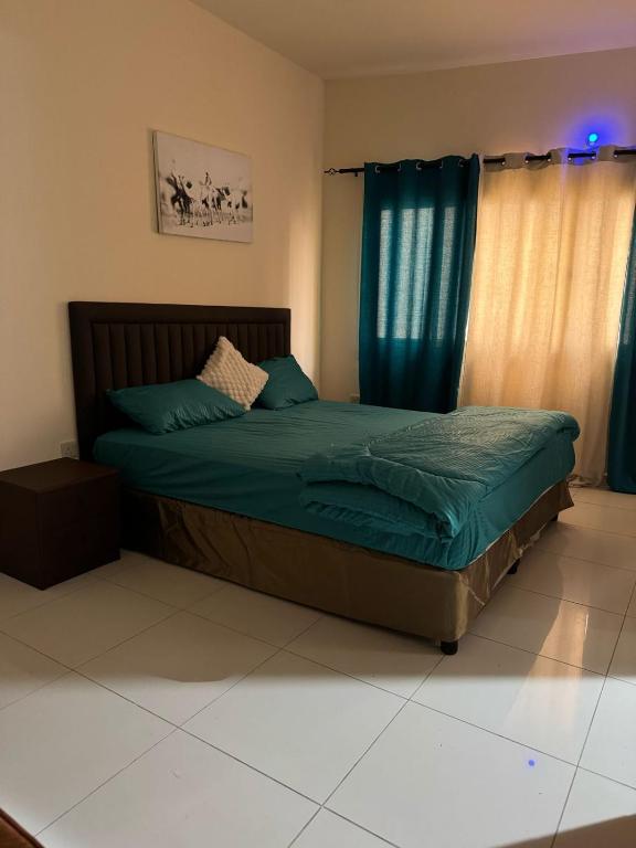 迪拜Fully Furnished Studio Appartment next to Sharaf DG metro Station的一间卧室配有一张带蓝色床单和蓝色窗帘的床。