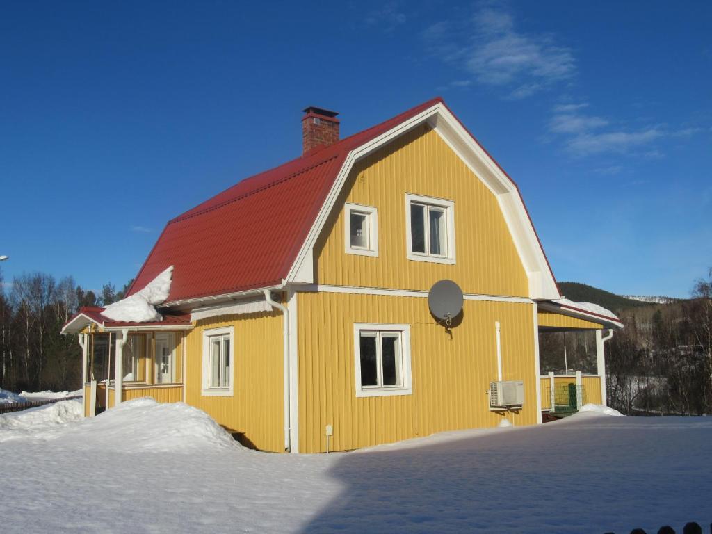 HammarstrandVilla Indalsälven的雪中带红色屋顶的黄色房子