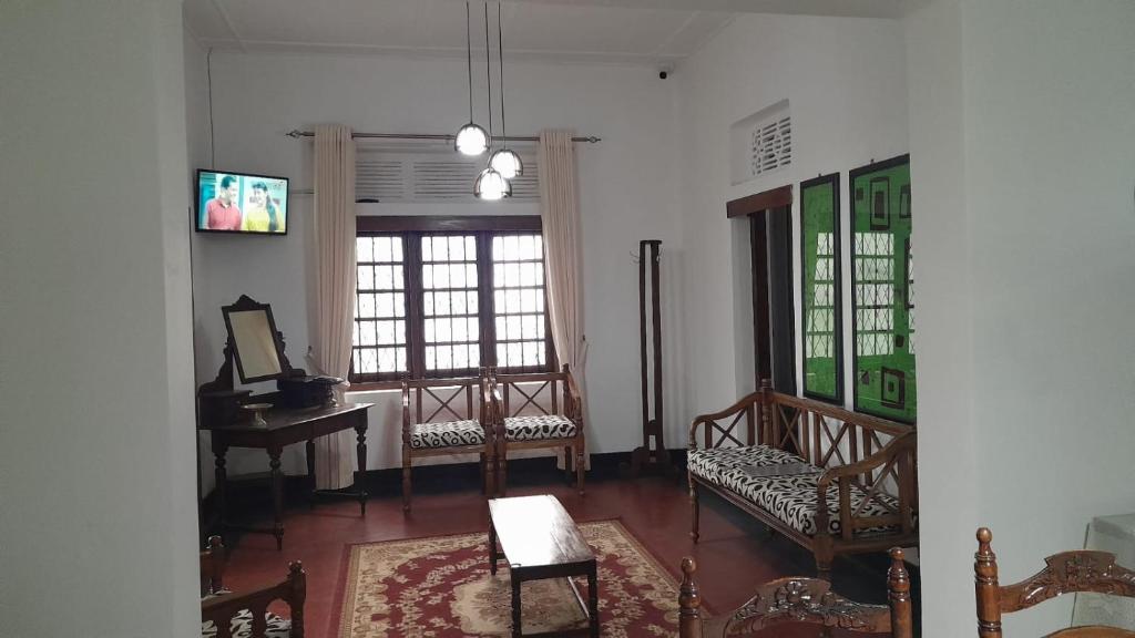 哈普特莱Rajavilla的客厅配有椅子和桌子,设有窗户
