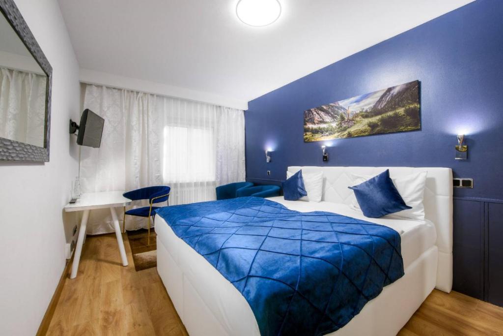 慕尼黑里沃利酒店的蓝色和白色的卧室配有一张床和一张书桌