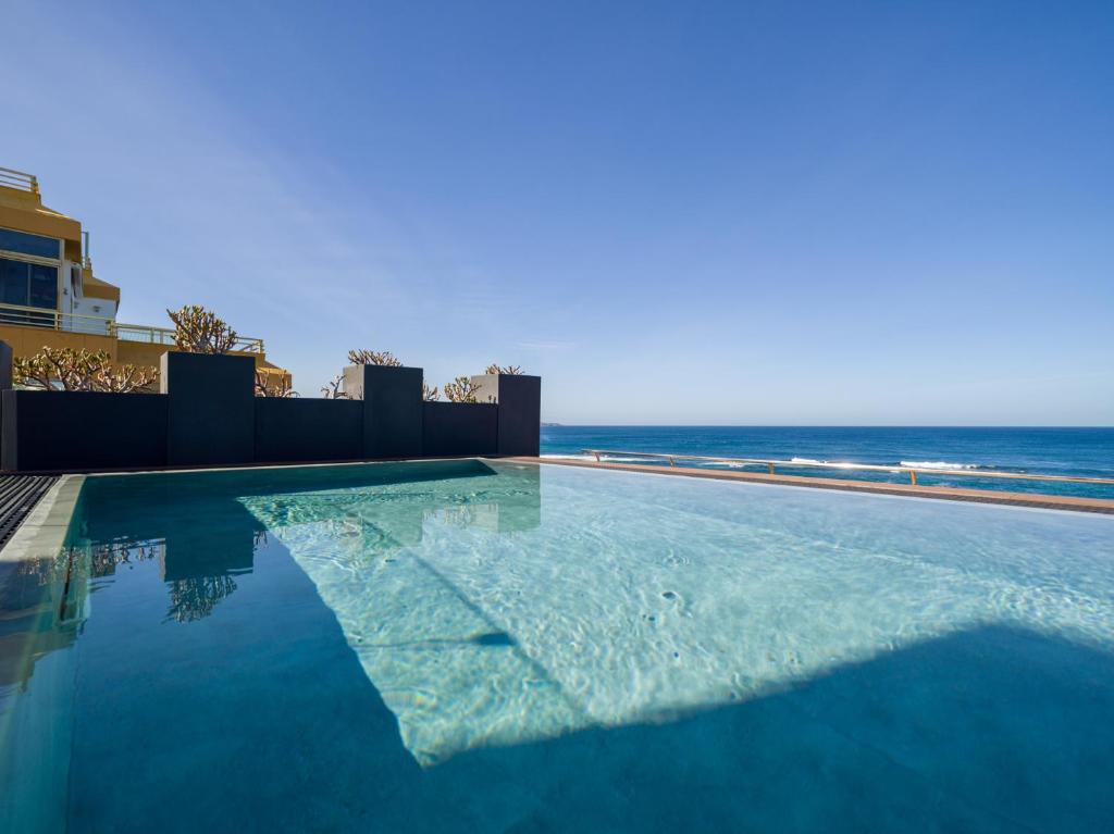 大加那利岛拉斯帕尔马斯Sercotel Playa Canteras的一座背景海洋的游泳池
