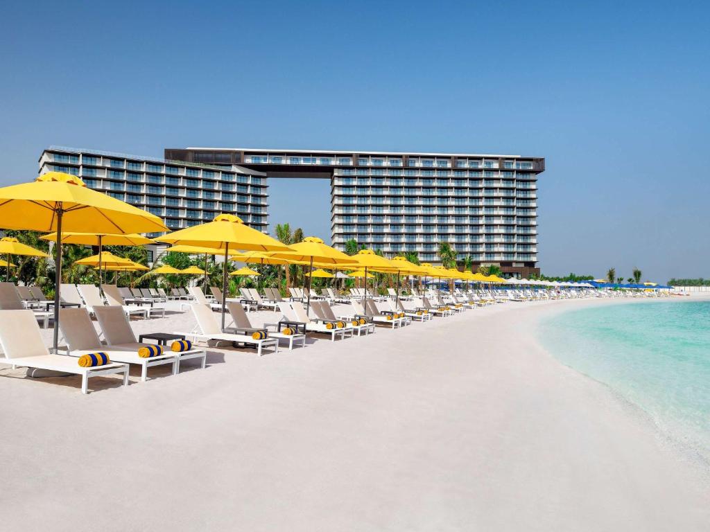 拉斯阿尔卡麦Mövenpick Resort Al Marjan Island的海滩上的一排椅子和遮阳伞
