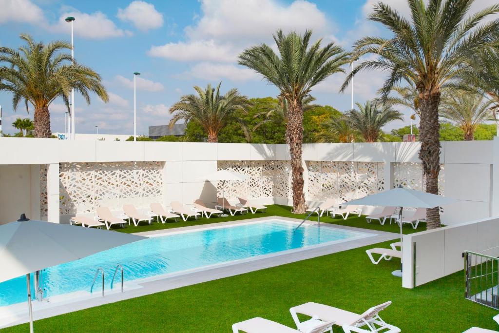 埃尔切埃尔切港酒店的一个带椅子的游泳池,棕榈树