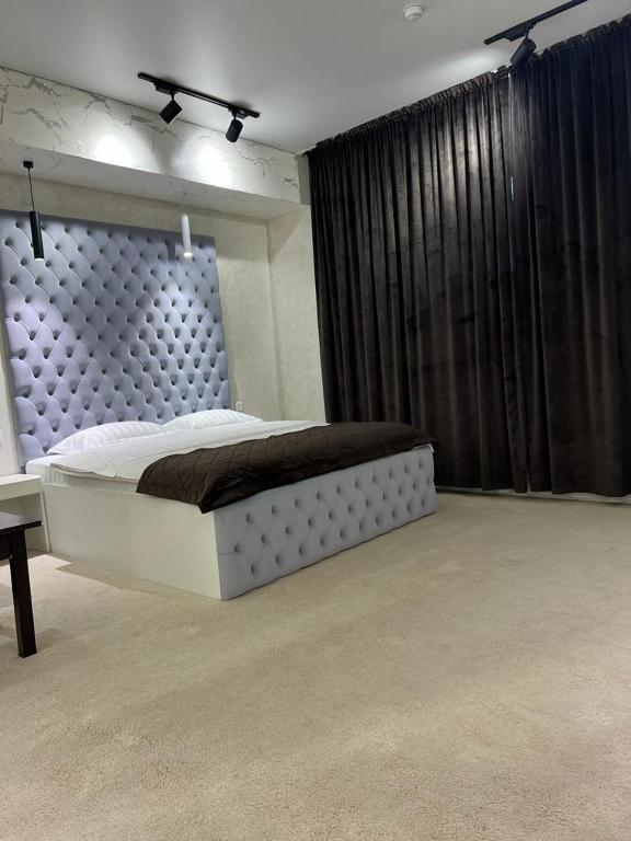 塔拉兹Al-Karakhan的一间卧室配有一张大床和黑色窗帘