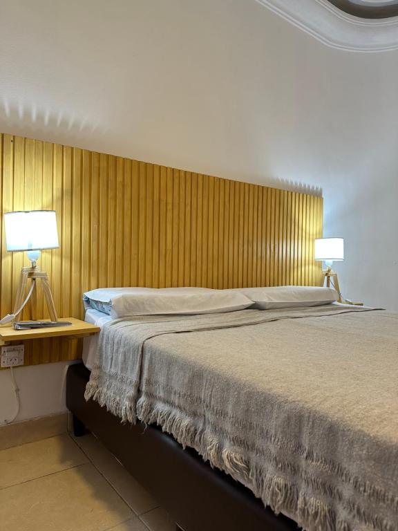 萨尔塔Petit Balcarce Salta的一间卧室配有一张床和一张桌子上的两盏灯。