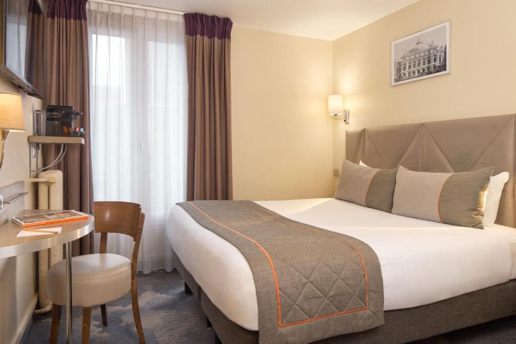 巴黎提姆巴纳斯峰酒店的酒店客房设有一张大床和一张书桌。