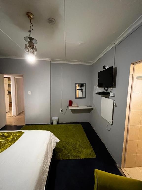 科克斯塔德E.G Guest House的卧室配有白色的床和绿色地毯。