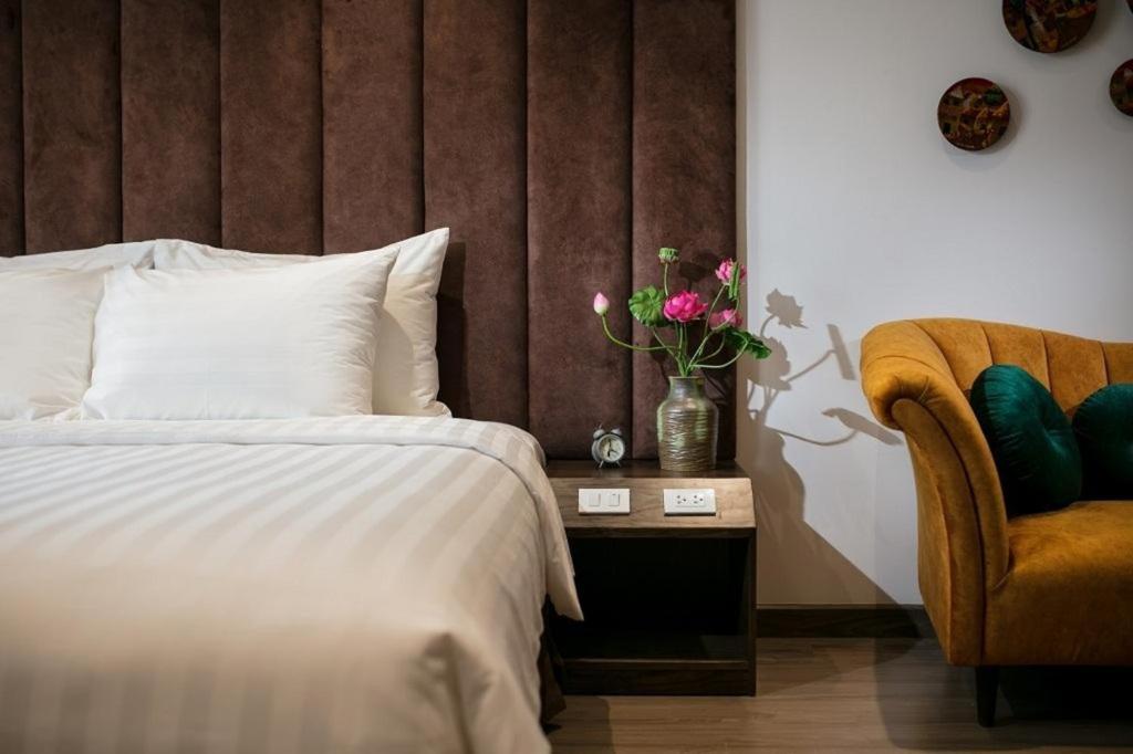 河内The Bloom Hanoi的一间卧室配有一张床、一把椅子和花瓶