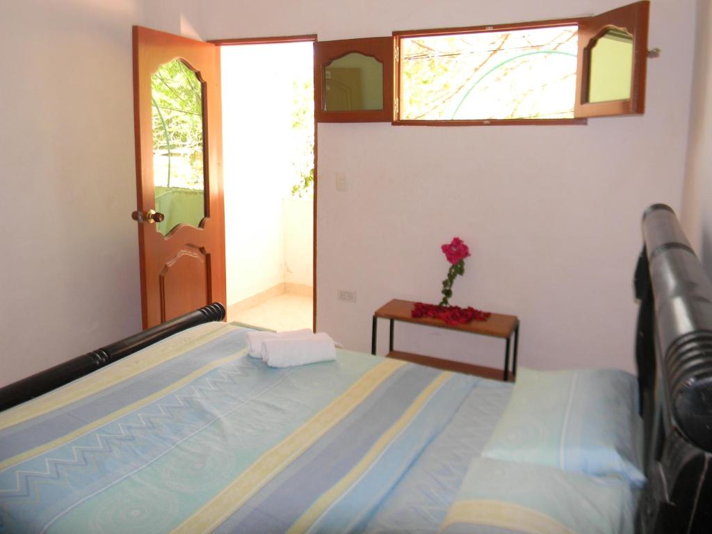 塔甘加HostalNativo的一间卧室,配有一张床,桌上有一朵花
