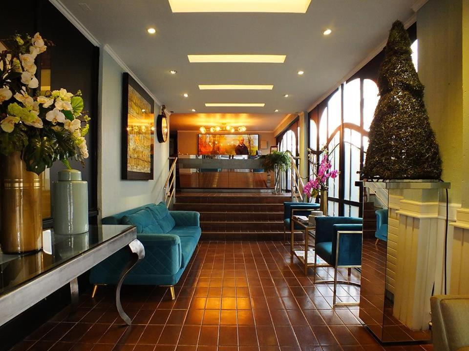 康塞普西翁HOTEL ALONSO DE ERCILLA的大楼内带蓝色沙发和椅子的大堂