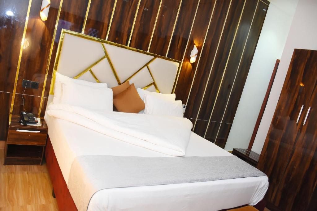 NnewiGrand Seasons Hotel, Nnewichi的卧室配有白色的床和木制床头板