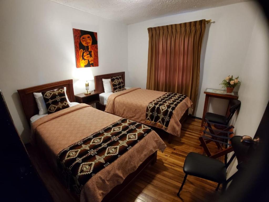 基多Apartamento 32 Juana de Arco的酒店客房,配有两张床和椅子