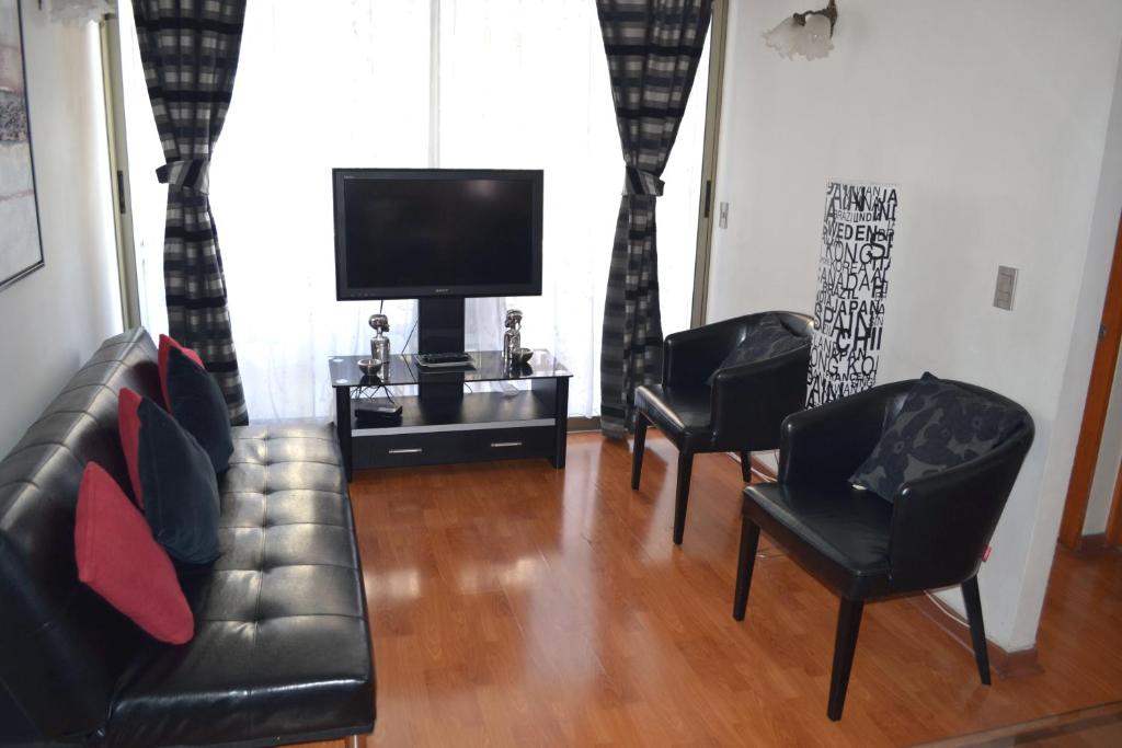 安托法加斯塔阿莫布拉多斯拉赫尔曼达迪公寓的客厅配有2把黑色皮革椅子和电视