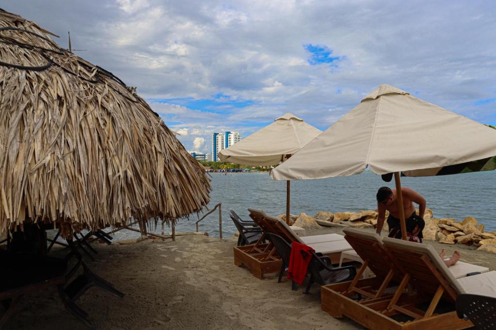 科韦尼亚斯Hotel Costa Mar Coveñas的坐在海滩上,在遮阳伞下的人