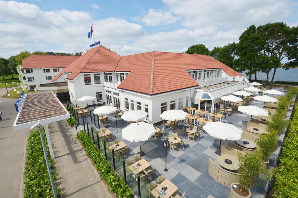 登博斯斯海尔托亨博斯弗莱彻餐厅酒店的享有带桌子和白色遮阳伞的建筑的顶部景色