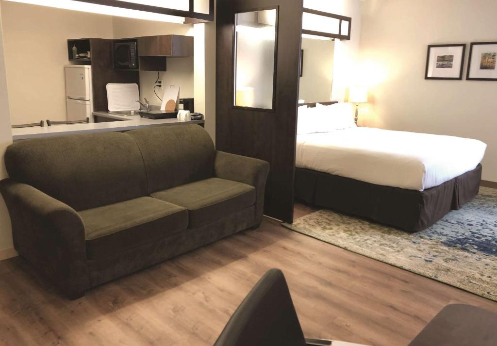 赫斯特Villa Inn & Suites - SureStay Collection by Best Western的客厅配有床、沙发、床和床。