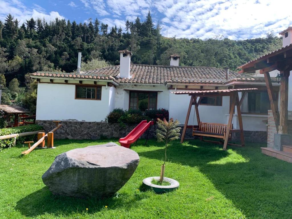基多Hacienda la campiña的院子里有红色滑梯和岩石的房子