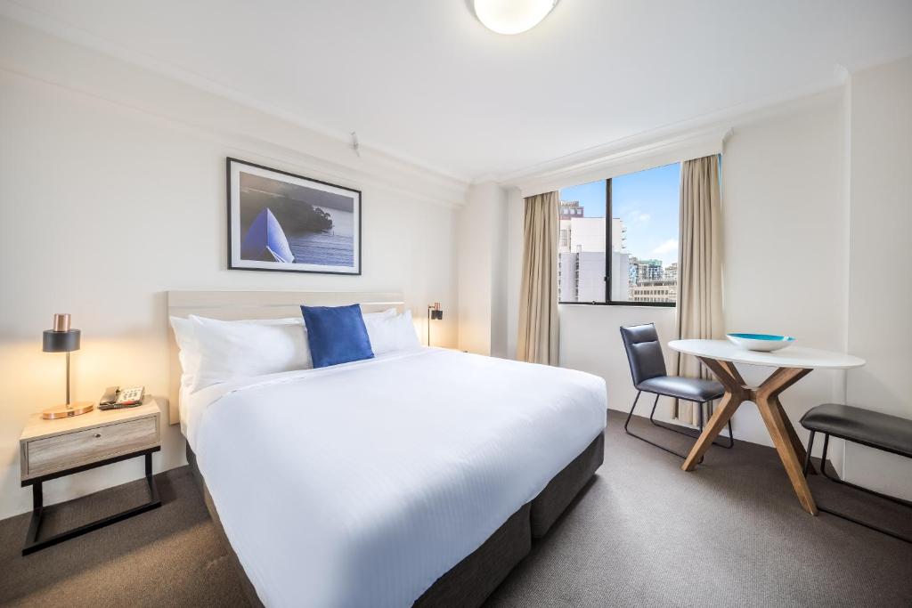悉尼Oaks Sydney Castlereagh Suites的酒店客房设有一张大床和一张桌子。