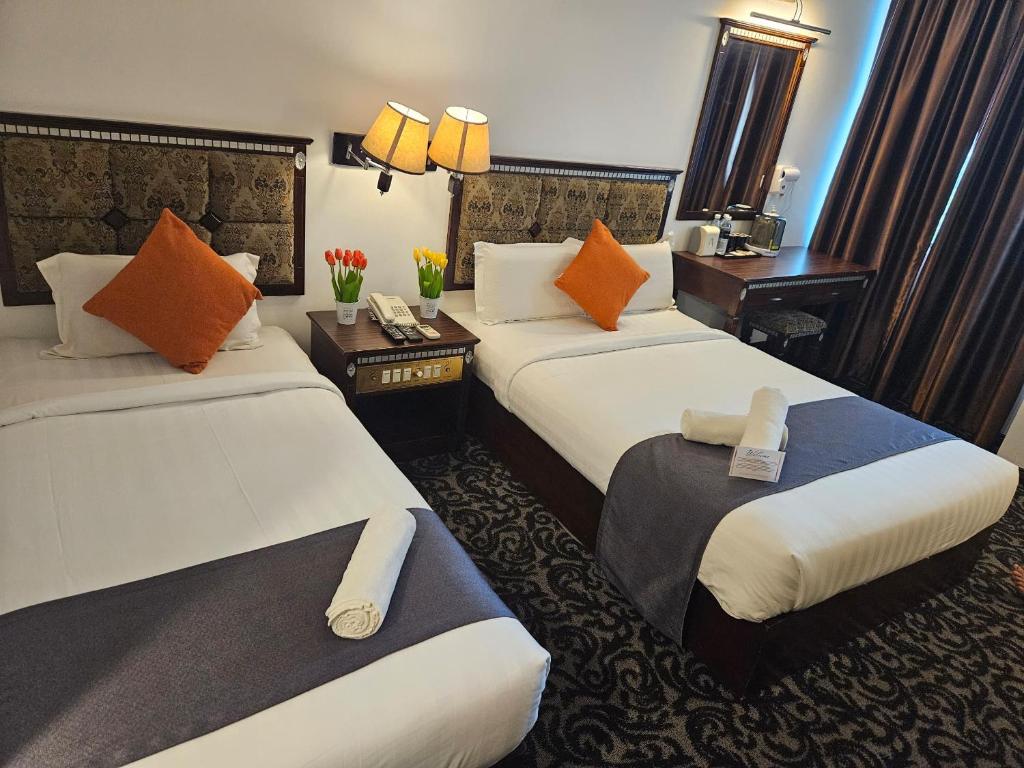 关丹Go Lodge Hotel Kuantan的酒店客房 - 带两张带橙色枕头的床