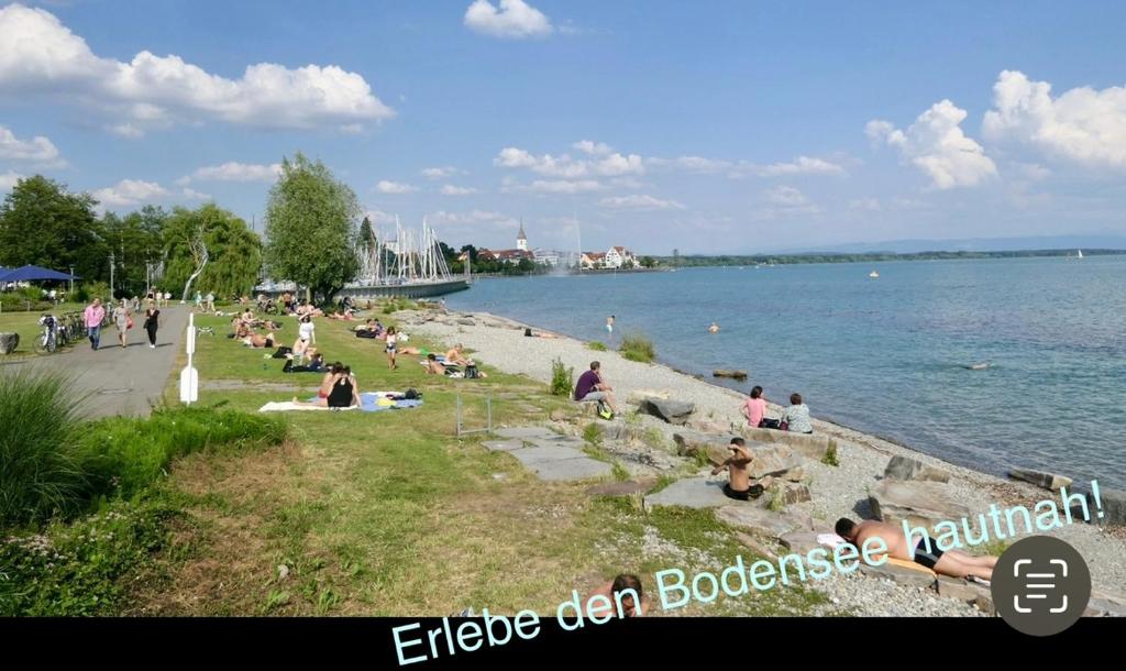 腓特烈港Ferienwohnung am Bodensee- zentrale Lage, free parking and wifi, 109 m2, privater Garten, 7 Gäste, 2x Kingsize Boxspringbett, familienfreundlich的一群人坐在海滩上靠近水面