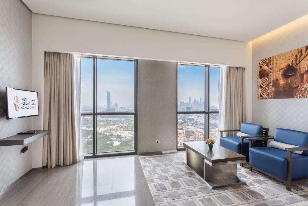 迪拜Spacious Studio Apartment in Hyatt Regency Dubai Creek Heights by the S Holiday Homes的客厅设有蓝色椅子和大窗户