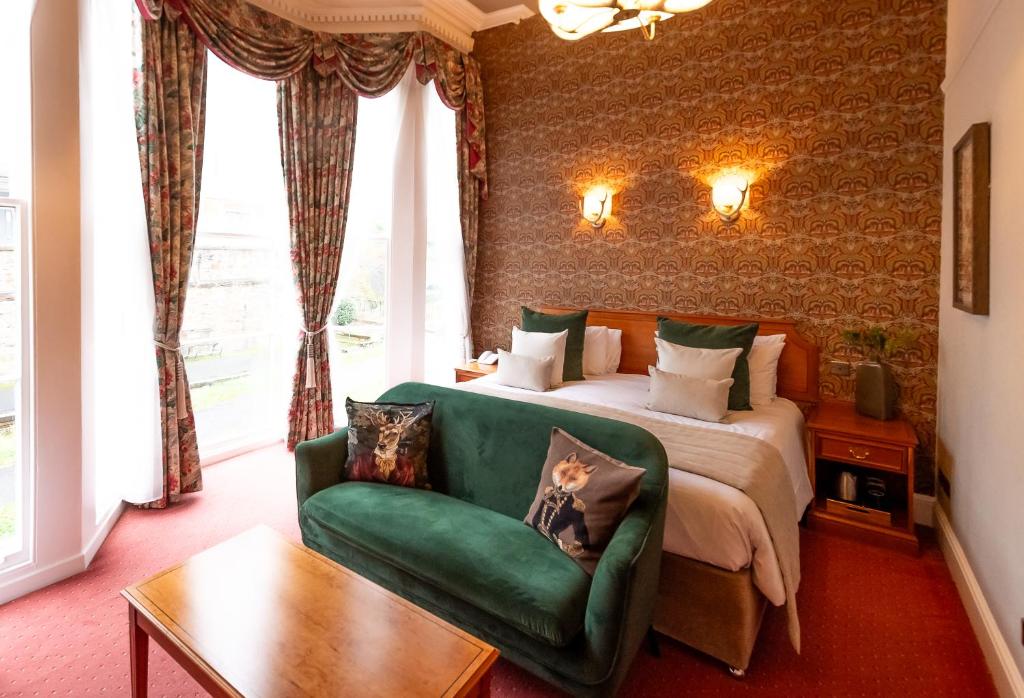比迪福德皇家酒店的一间卧室配有一张床和一张绿色沙发