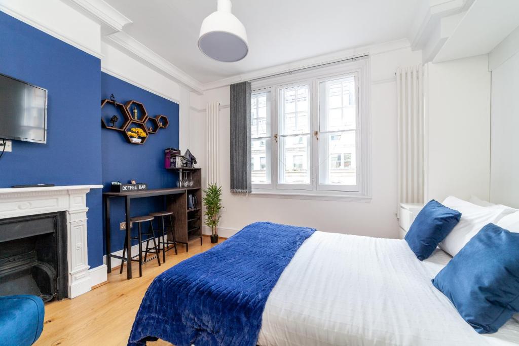 伦敦Cannon Street Studios的蓝色和白色的卧室设有一张床和一个壁炉