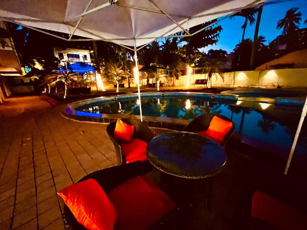 GoaShivam Resort With Swimming Pool ,Managed By The Four Season - 1 km from Calangute Beach的一个带桌椅的游泳池和一个帐篷