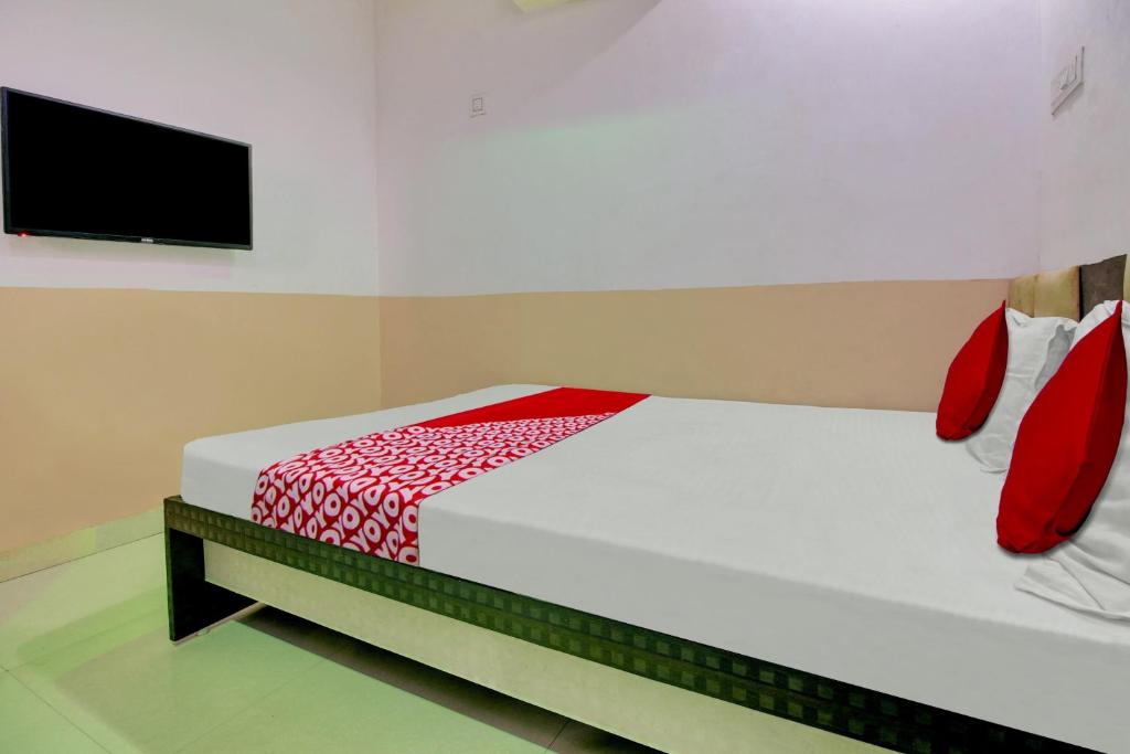 那格浦尔Super OYO Flagship Hotel Vinit Lodging的一间卧室配有一张带红色床单的床和一台平面电视。