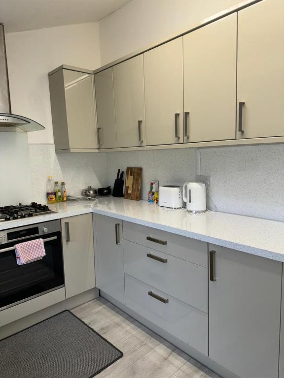 卡迪夫Cardiff Grangetown Stylish 3Bed House.的厨房配有白色橱柜和炉灶烤箱。