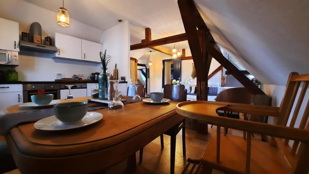 EckwersheimCharmant Appartement proche Strasbourg à Eckwersheim的厨房里一张木桌,上面放有盘子和碗