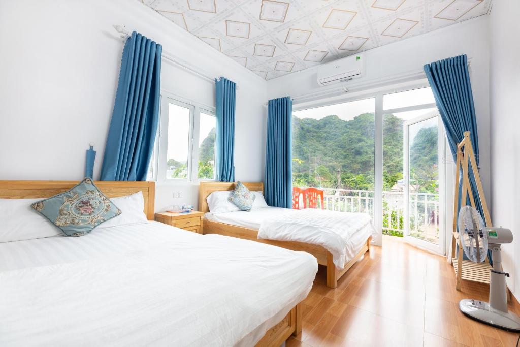 吉婆岛Cat Ba Countryside Homestay的配有蓝色窗帘的客房内的两张床