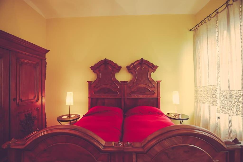PortacomaroHistoric and quiet house in the Langhe&Monferrato的一间卧室配有一张红色大床和两盏灯