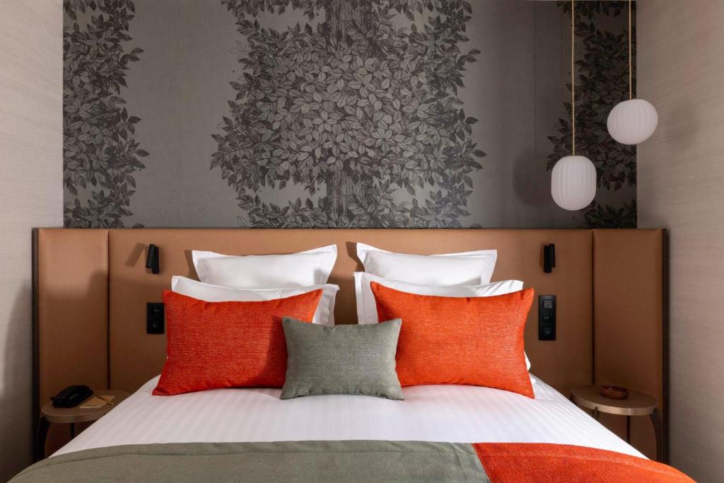 巴黎Hôtel L'Ormaie & Spa的一间卧室配有橙色和灰色枕头。
