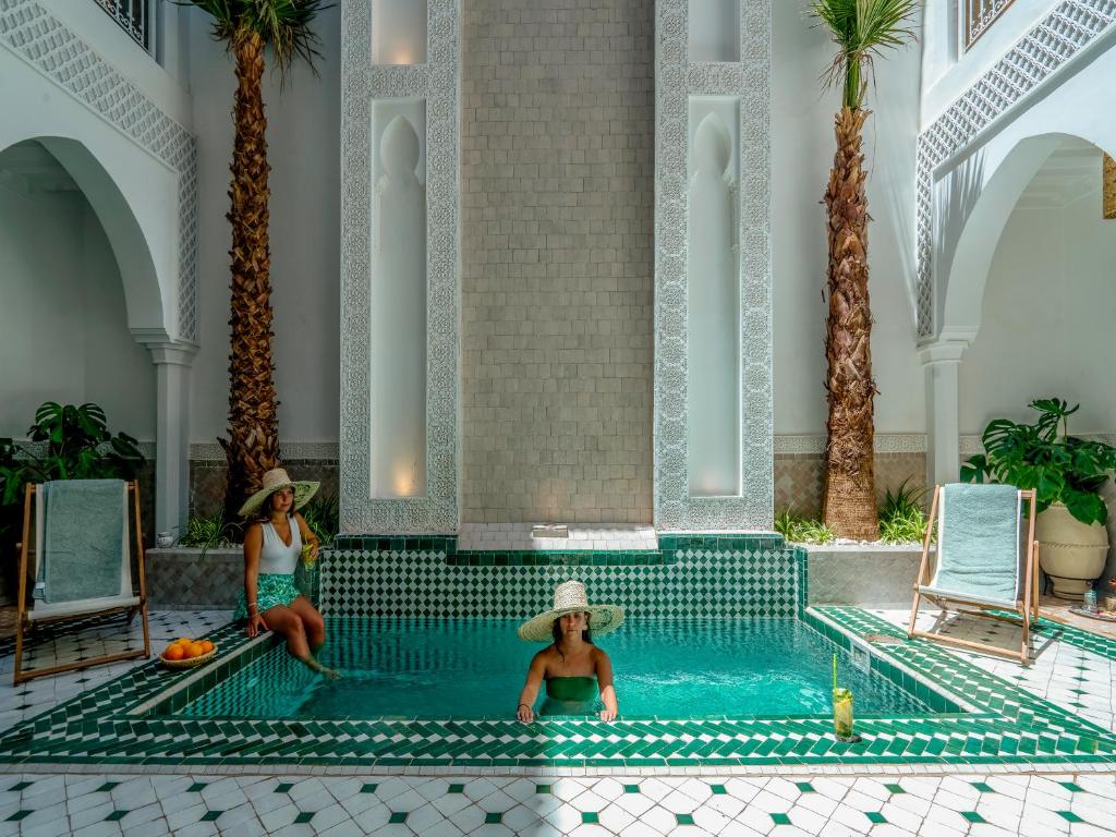 马拉喀什Riad Nelia De Marrakech Hotel Boutique & Spa的两名妇女在度假村的游泳池里
