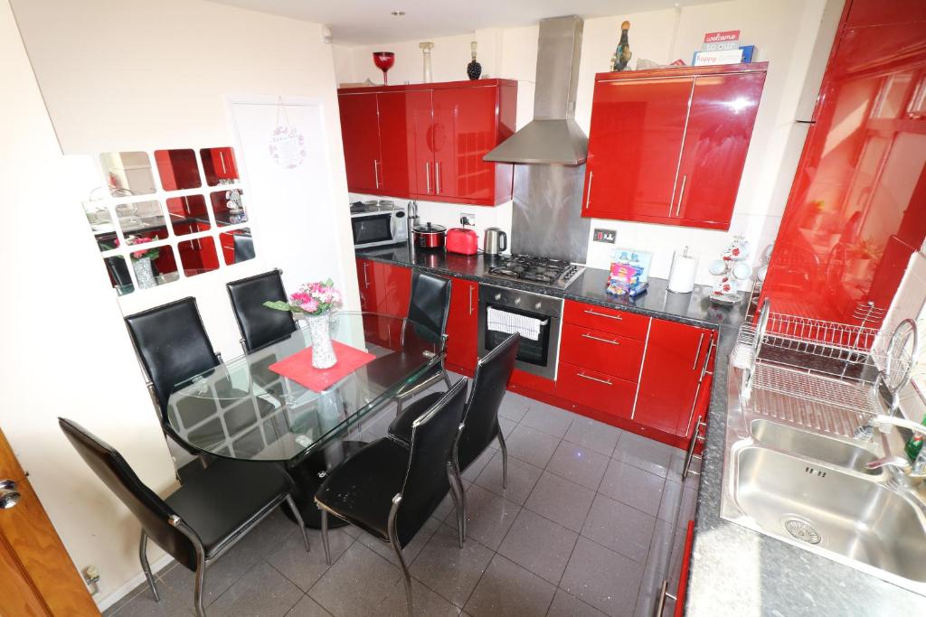 伦敦3 Bedroom House-Garden-Stratford-Olympic Park的厨房配有红色橱柜和玻璃桌椅