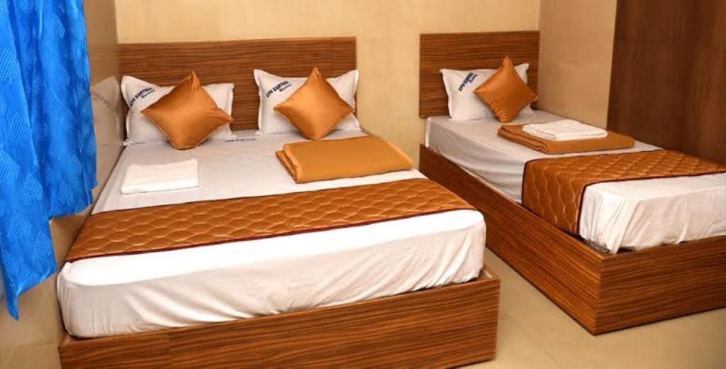孟买HOTEL COSTA DEL的配有蓝色窗帘的客房内的两张单人床