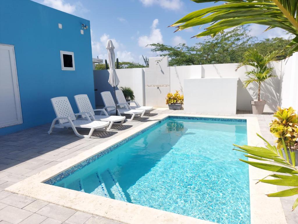 努尔德Apricity Suites Aruba的一个带椅子的游泳池以及蓝色的房子
