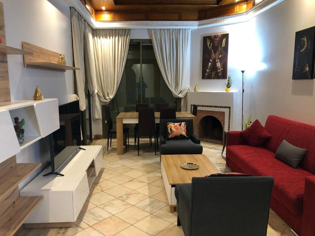 马拉喀什Appartements de charme à la palmeraie的客厅配有红色的沙发和桌子