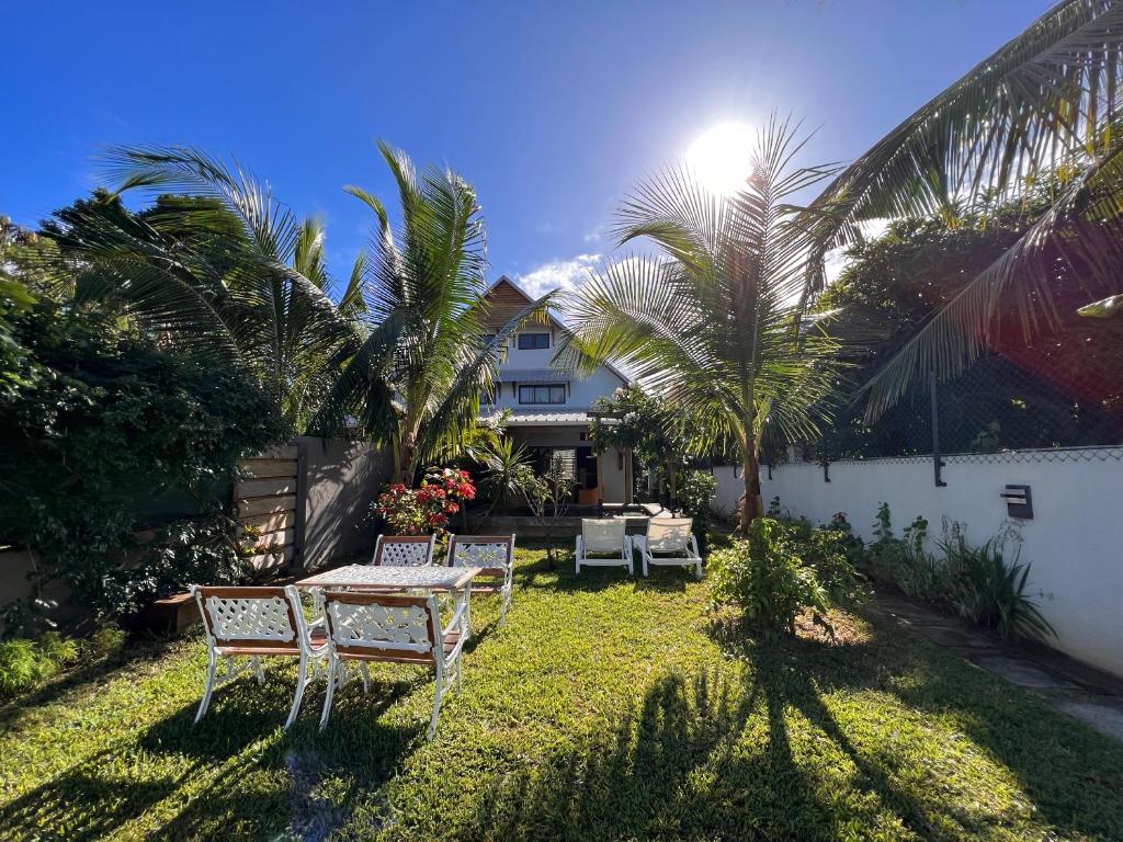 格兰贝伊Tropical 3-bedrooms Coastal Residence Creolia的后院配有桌椅和棕榈树