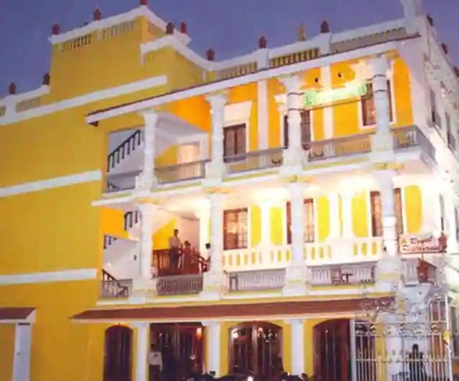 蓬蒂切里Hotel Soorya Inn的一座黄色的大建筑,阳台上有人