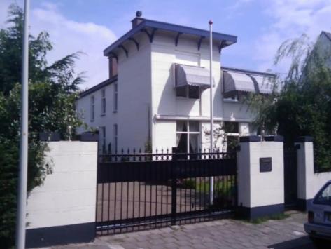 斯海弗宁恩Villa Insulinde的白色的房子,有门和栅栏
