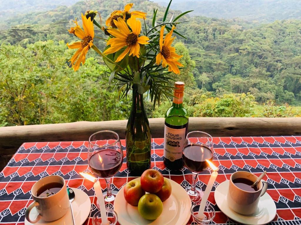 BuhomaBwindi Neckview Lodge的一张桌子,上面放着一瓶葡萄酒和一瓶鲜花