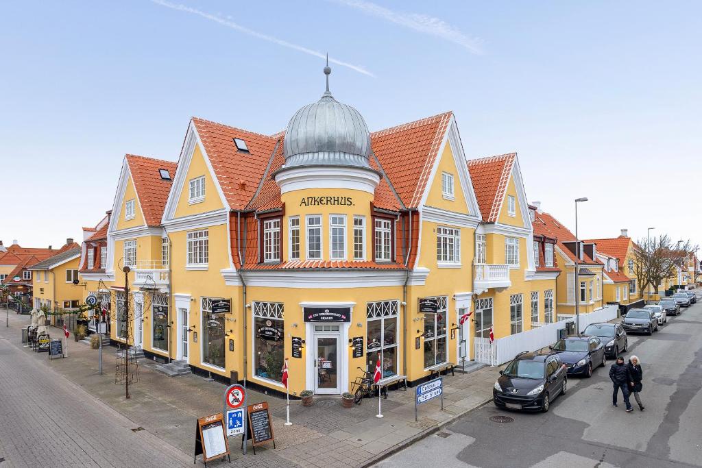 斯卡恩Ankerhus Skagen的一条街道上一座黄色的大建筑,有停放的汽车