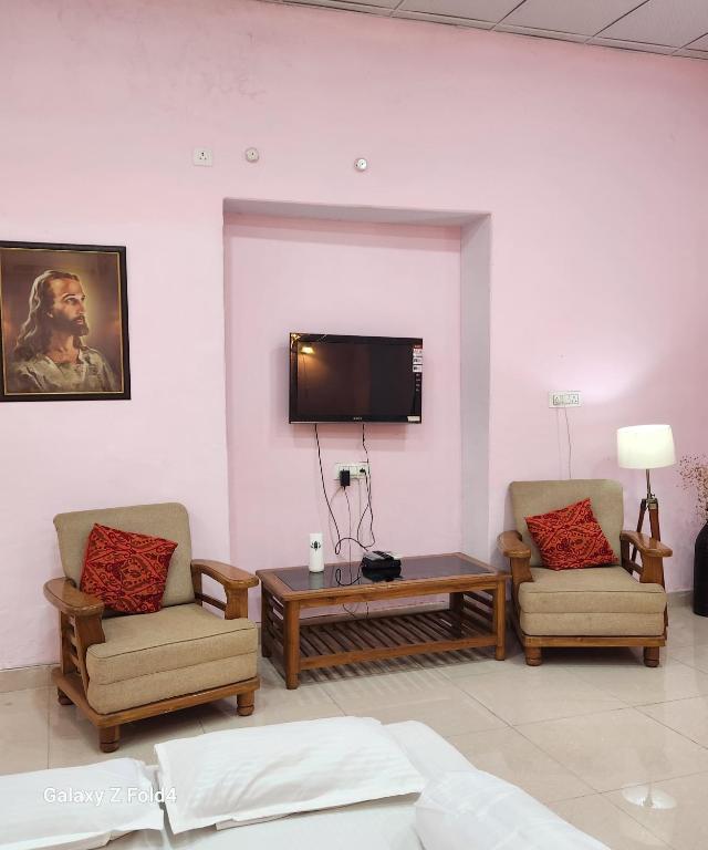 PrayagrajNICTBS的客厅配有两把椅子和墙上的电视