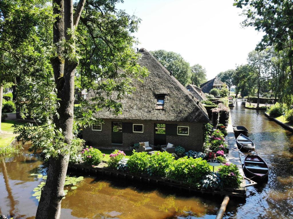 羊角村Plompeblad Guesthouse Giethoorn的河中带船的房子