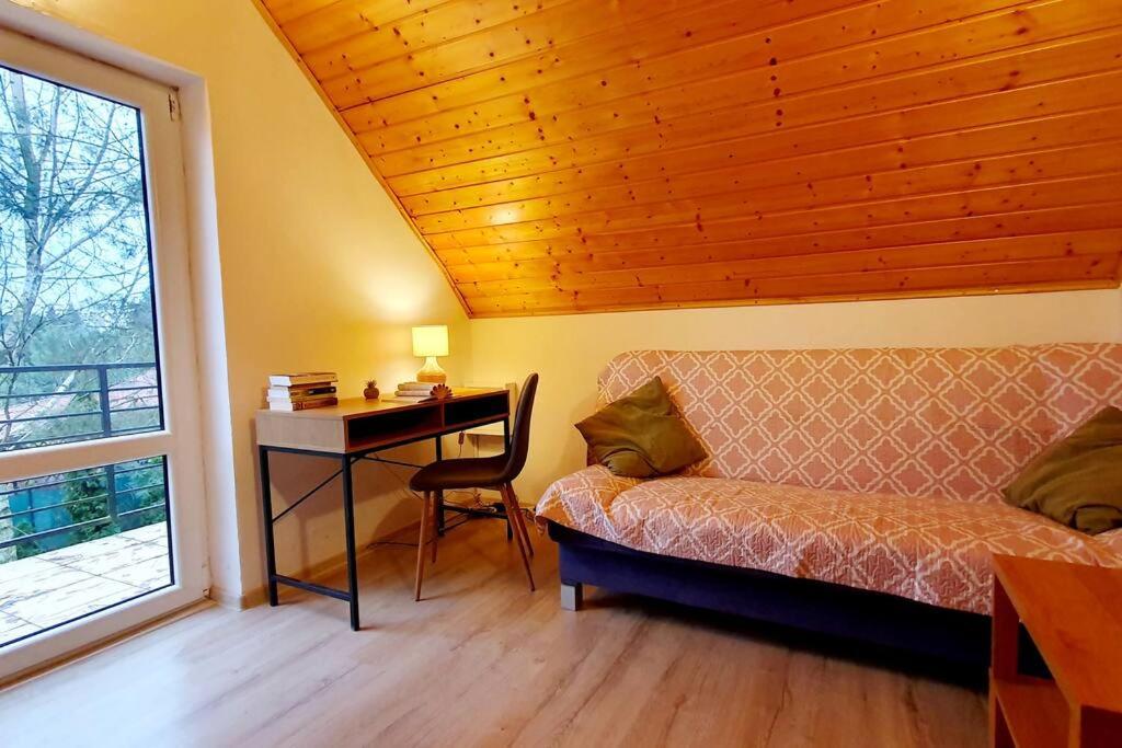 Całoroczny domek nad Jeziorem Piaseczno的卧室配有一张床和一张书桌,毗邻窗户
